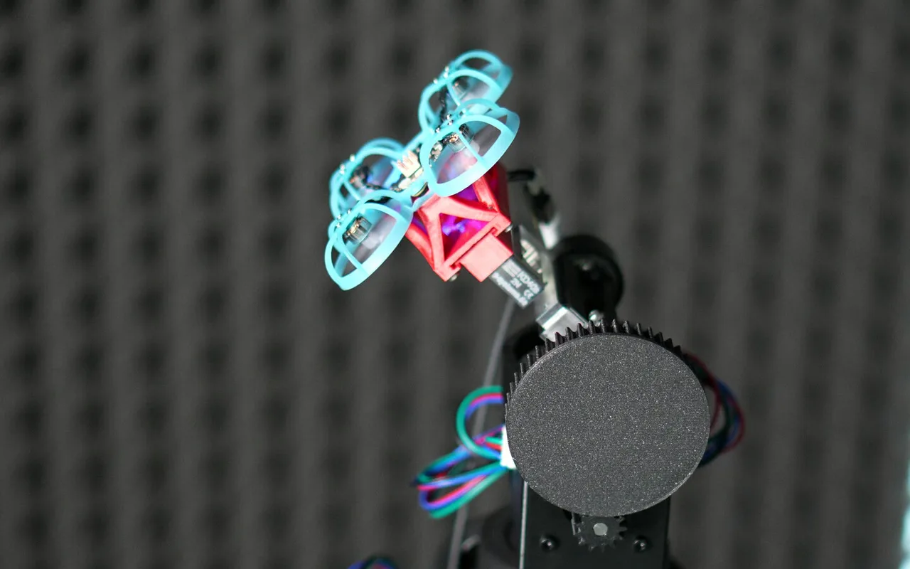 A Tornyol microdrone with cyan prop guards, mounted on a test rig