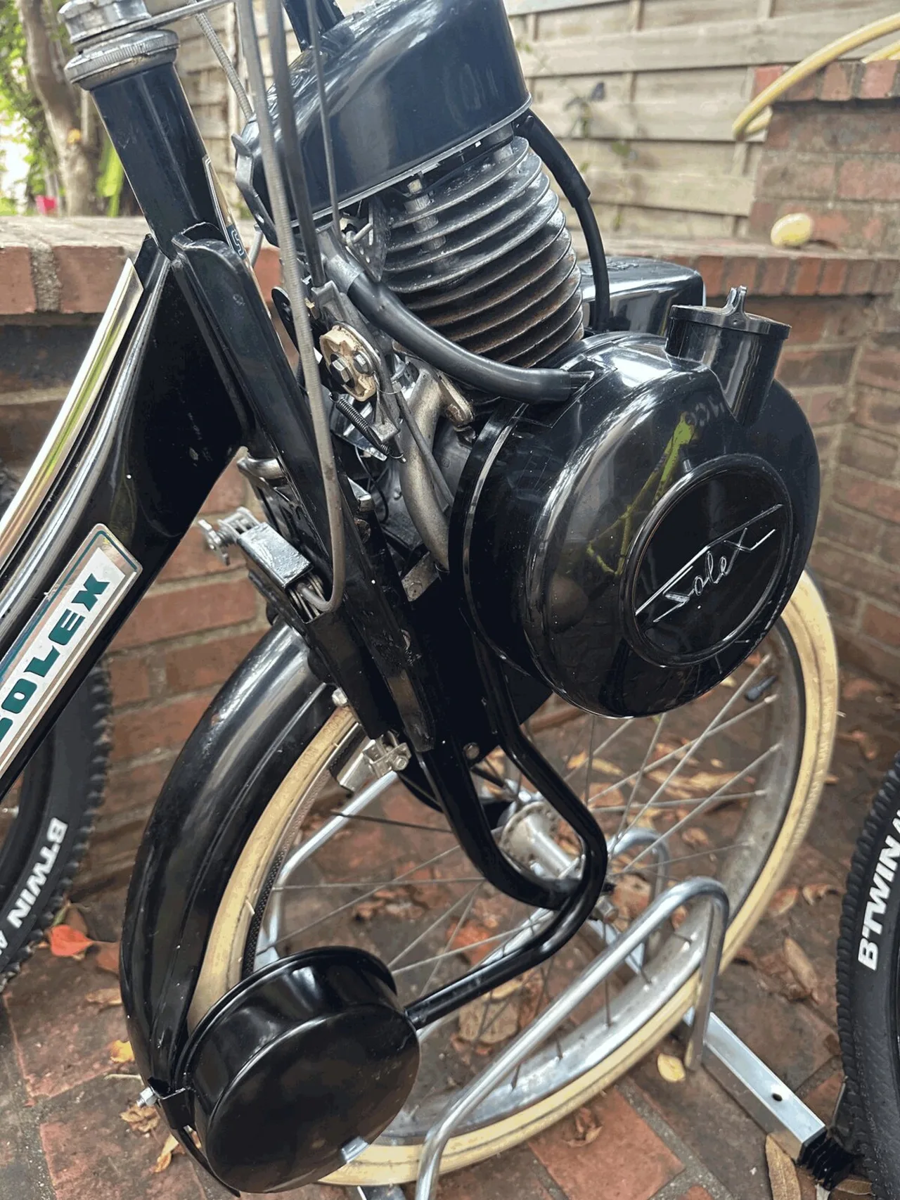The rebuilt Solex engine, glossy black, mounted over the front wheel of the moped