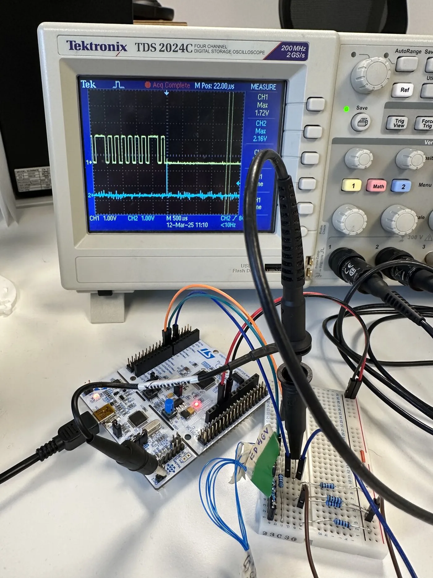 Tektronix oscilloscope showing an I2C burst, probing a breadboard wired to an ST Nucleo board