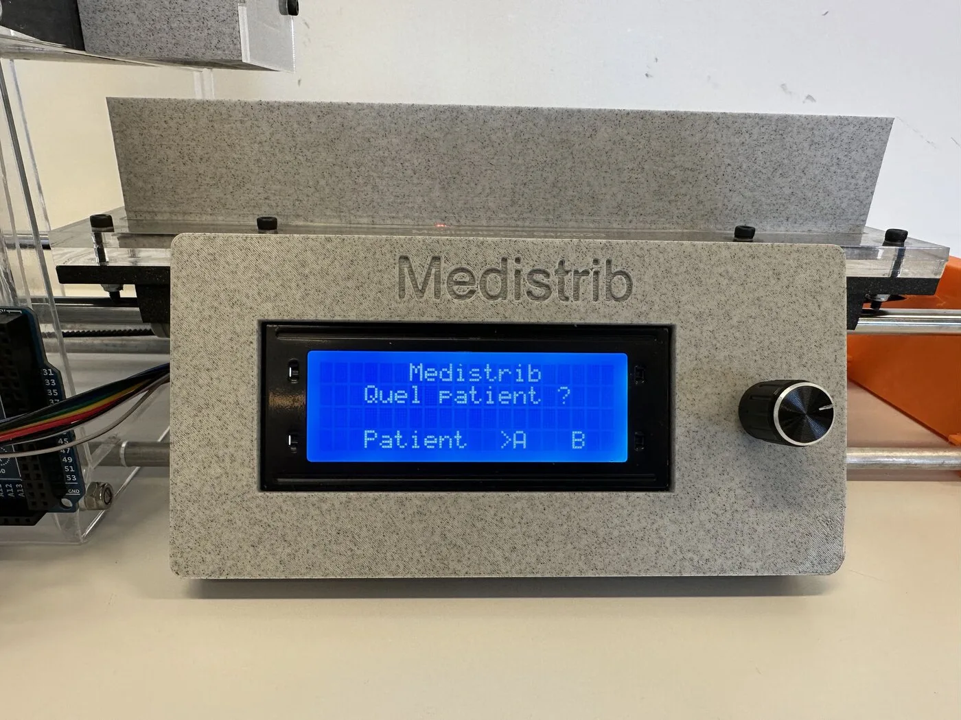 A 3D-printed panel with an LCD reading Medistrib, Quel patient, Patient A or B, and a knob