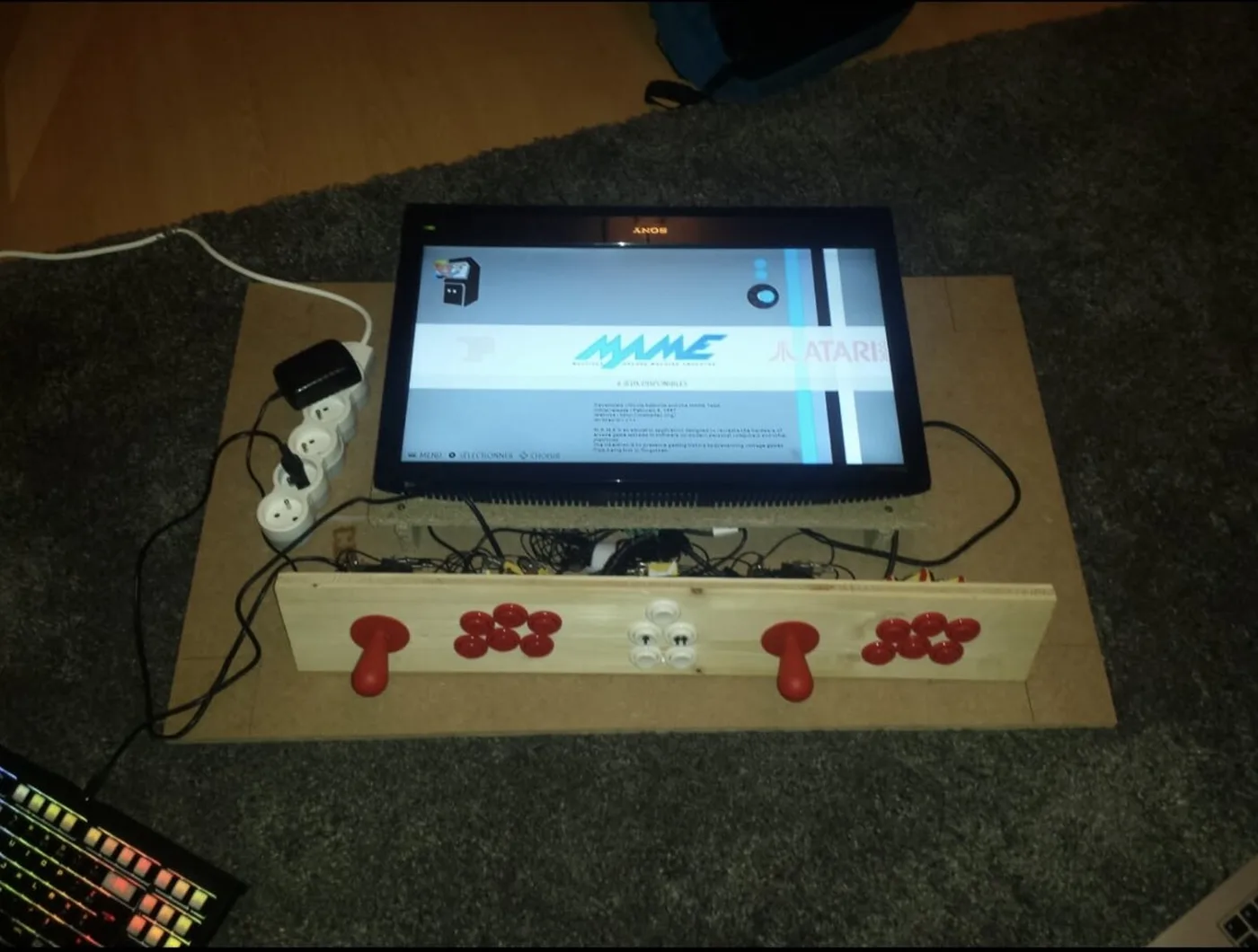 The control panel and screen wired up on the floor before the table was built, showing the MAME menu
