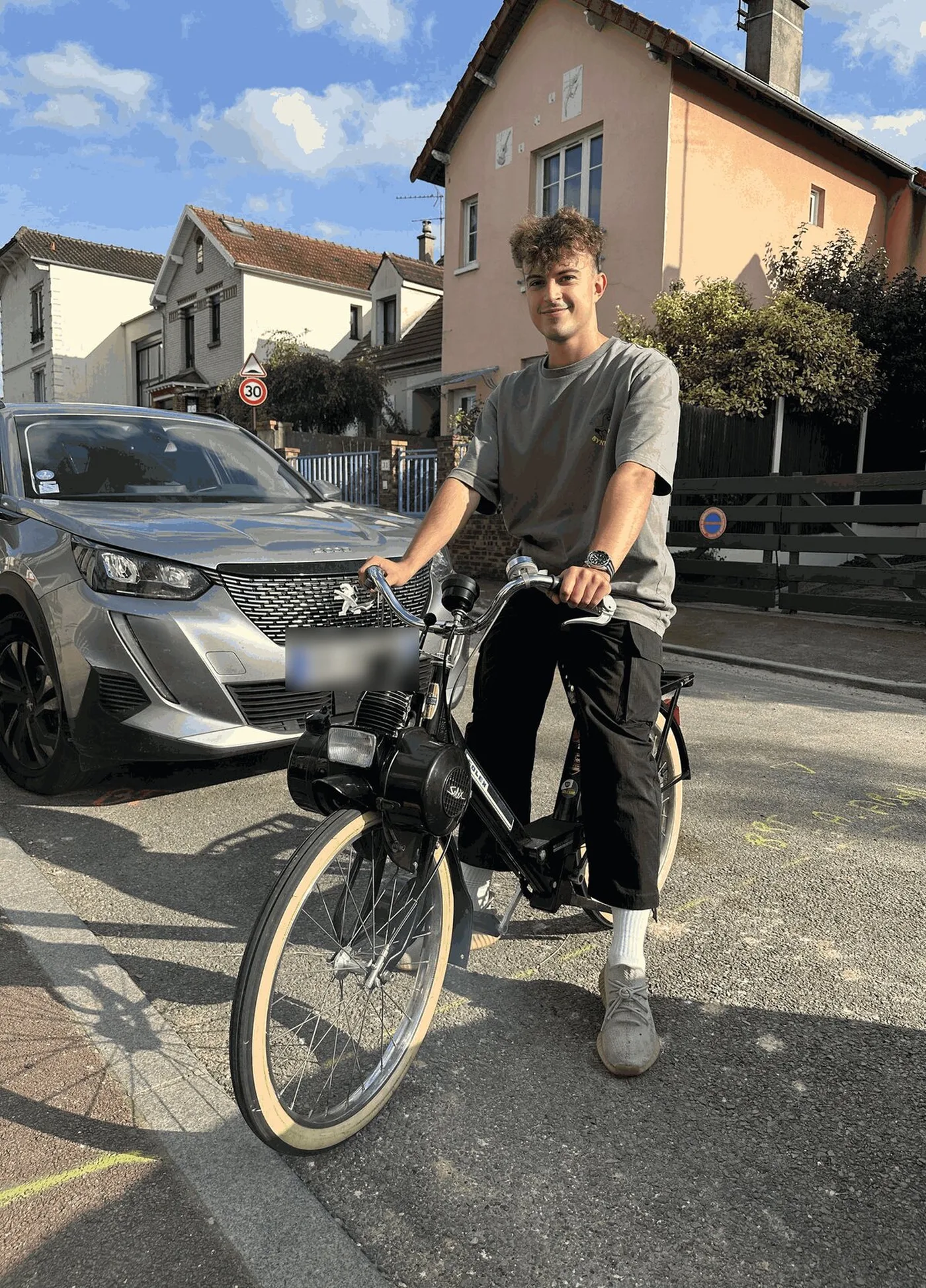 Me sitting on the black VéloSoleX moped in a residential street