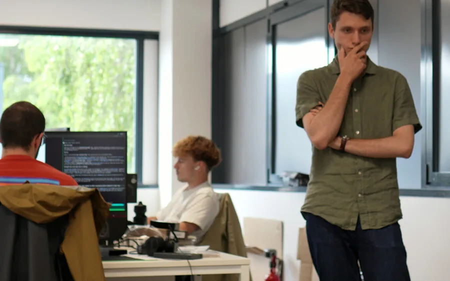 The Tornyol office: two engineers at their desks and one standing, with a drone on a stand on the right