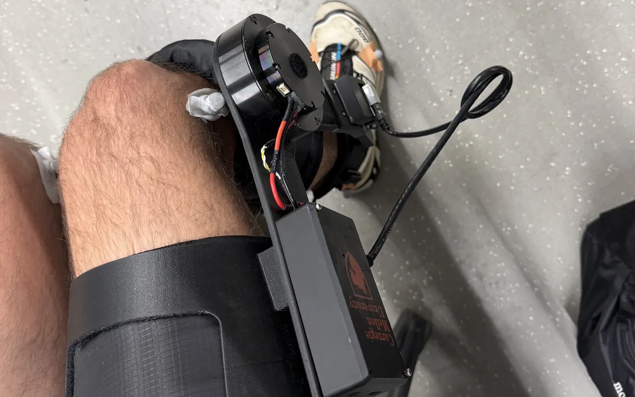 Looking down at my knee wearing the exoskeleton: thigh cuff, knee motor and electronics box